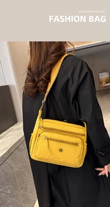 Detail of yellow nylon crossbody bag with multi-zipper pockets and adjustable strap