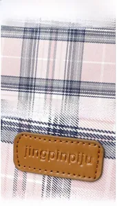 Close-up of pink plaid fabric texture and brown leather logo patch with stitching