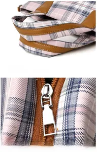 Detail of pink plaid tote bag featuring brown faux leather handles and silver zipper pull