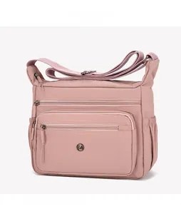 Detail of dusty pink nylon shoulder bag showing multiple zipper pockets and metal logo