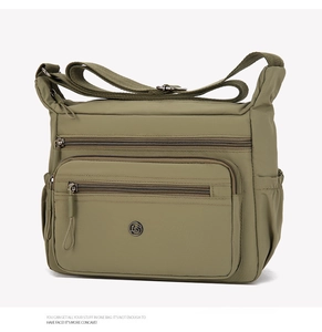 Detail view of the olive green nylon crossbody bag showing multiple zipper pockets and logo
