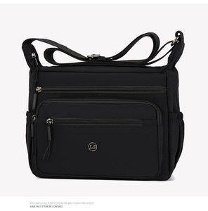 Detail of black nylon crossbody bag with three front zipper pockets and adjustable strap