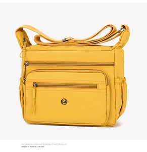 Detail view of the bright yellow crossbody bag with multiple zippers and wide strap