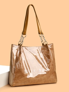 Gros plan sur un sac cabas marron brillant avec chaîne argentée et lettrage TOTE BAG