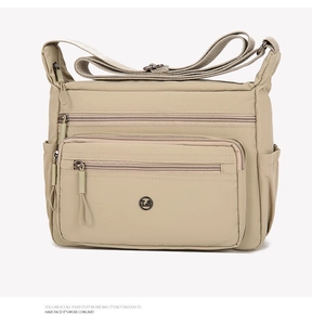 Detail view of khaki nylon crossbody bag with multiple zippers and adjustable strap