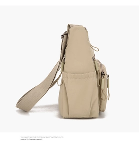 Side view of beige nylon crossbody bag featuring adjustable straps and layered zippers