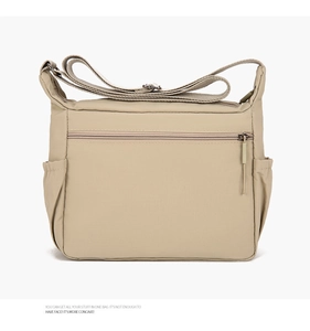 Detail of khaki nylon crossbody bag featuring front zipper pocket and side elastic pouches