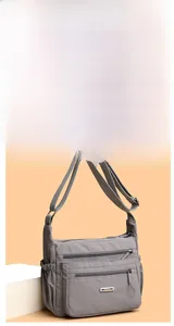 Detail view of large grey nylon shoulder bag with multiple zip pockets and adjustable strap