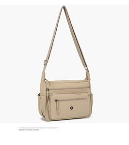 Detail of khaki nylon crossbody bag showing multiple zip pockets and side bottle holder