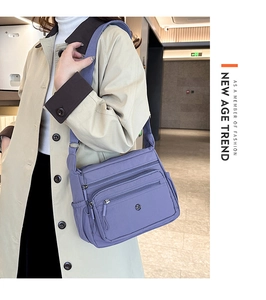 Detail of purple nylon crossbody bag with multi-zipper pockets and wide strap