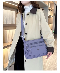 Close-up of lightweight purple nylon crossbody bag with multi-zipper compartments