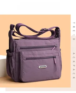 Macro detail of dark purple waterproof nylon bag with multi-pocket zippers and metal logo