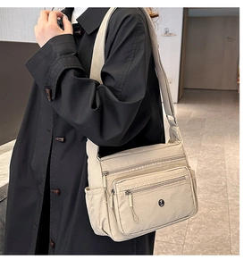Detail of beige nylon crossbody bag with multi-pocket design and adjustable wide strap
