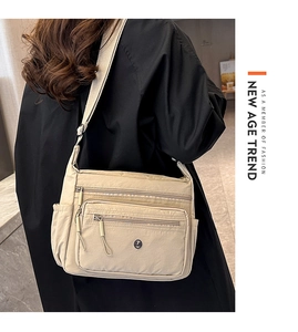 Detail of beige nylon crossbody bag with multi-zipper pockets and adjustable strap