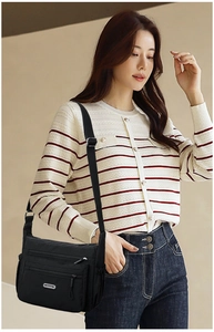 Detail of black nylon crossbody bag featuring multiple zipper pockets and adjustable strap