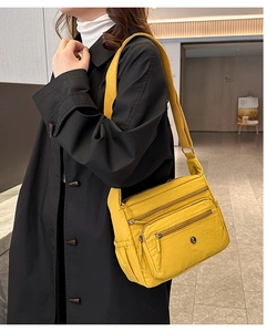 Detail of bright yellow multi-pocket nylon crossbody bag with adjustable wide strap