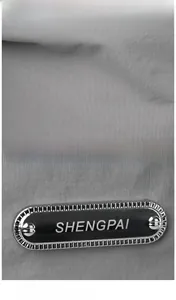 Macro shot of grey nylon fabric and polished black metal logo plate on shoulder bag