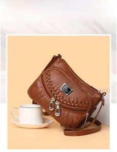 Detail of brown faux leather crossbody bag with woven trim and double zipper pockets