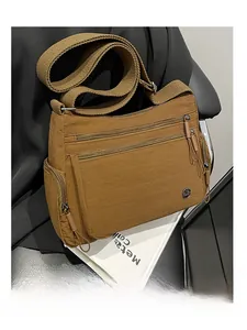 Detail of a brown nylon crossbody bag featuring multi-zipper pockets and wide woven strap
