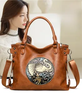 Detail of a brown vintage tote bag with an embossed elephant circular metal badge