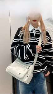 Detail of multi-pocket off-white oxford cross-body bag worn by a casual model
