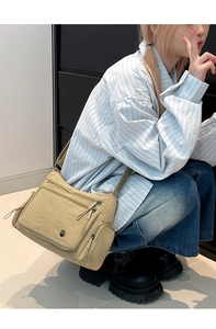 Macro detail of khaki oxford cloth crossbody bag with multiple zipper pockets and wide strap