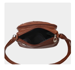 Top view of brown soft leather crossbody bag showing multi-zip compartments and interior