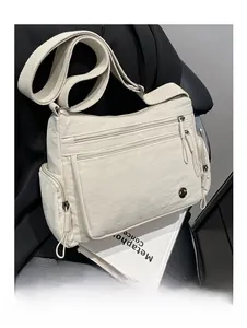 Detail of cream nylon crossbody bag featuring multiple zipper compartments and wide strap