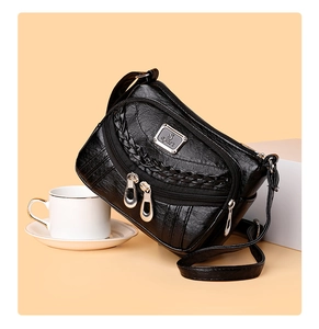 Detail of black faux leather crossbody bag with multiple zippers and woven texture
