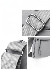 Détail de la quincaillerie métallique argentée et du tissu en nylon d'un sac gris