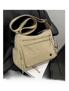 Detail view of large capacity beige nylon crossbody bag with multi-zippered pockets