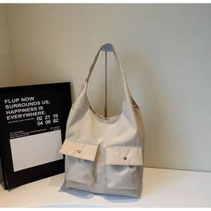 Detail einer minimalistischen beigen Canvas-Tasche mit zwei Taschen und silbernen Schnallen