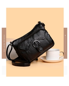 Detail view of black wrinkled faux leather bag with multi-layer zippers and metal rings