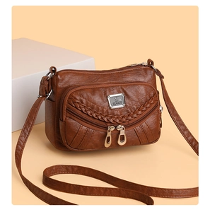 Detail view of dark brown soft leather crossbody bag with multi-layer zippers and S-sport logo