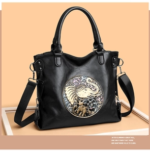 Detail of black tote bag with embossed elephant motif and removable woven shoulder strap