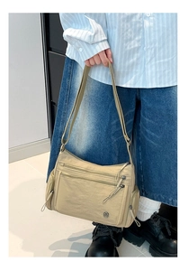 Detail view of khaki Oxford fabric crossbody bag with multiple functional zipper pockets