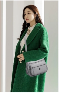 Sac bandoulière gris en nylon forme demi-lune avec plusieurs zips et sangle ajustable sur mannequin