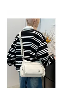 Detail view of cream Oxford fabric crossbody bag with multi-pockets and adjustable strap