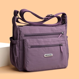Purple nylon shoulder bag with multiple zippered compartments and adjustable strap