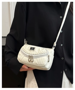 Close-up of white soft leather crossbody bag with lychee texture and dual zip pockets