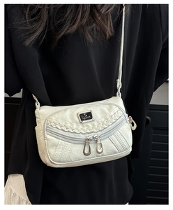 Detail view of white soft faux leather crossbody bag with multiple zippers and S-sport logo