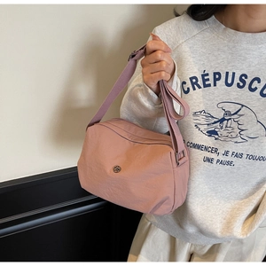 Detail of dusty pink nylon crossbody bag showing the fabric texture and adjustable strap