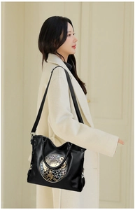 Detail of black leather tote bag with round bohemian elephant relief and canvas strap