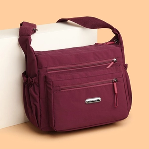 Versatile burgundy nylon shoulder bag with multiple zippered pockets and metal logo