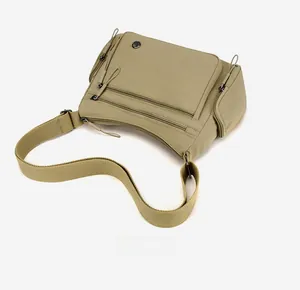 Detail of khaki green nylon crossbody bag showing multiple pockets and metal logo