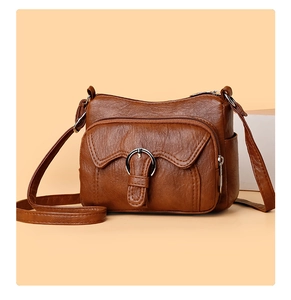 Detailed front view of brown leather crossbody bag with multiple zip pockets and ring buckle