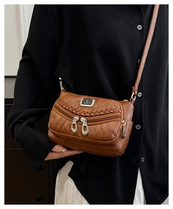 Detailed macro view of brown faux leather texture and weaving on a multi-zip crossbody bag