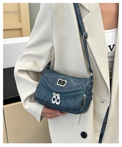 Detail of teal crossbody bag with woven trim, multi-zipper pockets and S sport metal logo