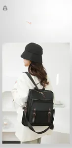 Dettaglio zaino in nylon nero con tiretti in pelle marrone su blazer bianco elegante