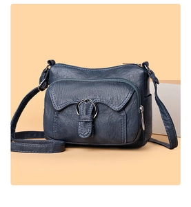 Detail of navy blue leather crossbody bag showing functional multi-zipper pockets and metal ring
